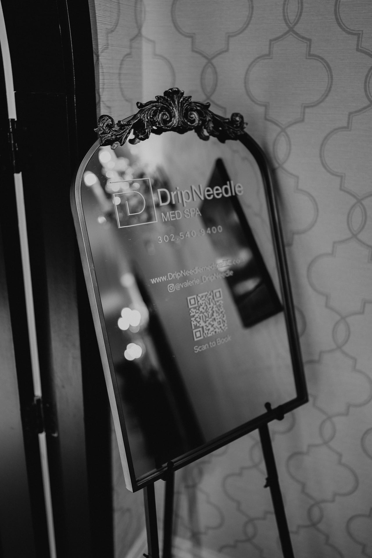 A mirror with DripNeedle Med Spa information on it. It includes phone number 302-540-9400, website www.dripneedlemedspade.com, instagram handle @valerie_DripNeedle